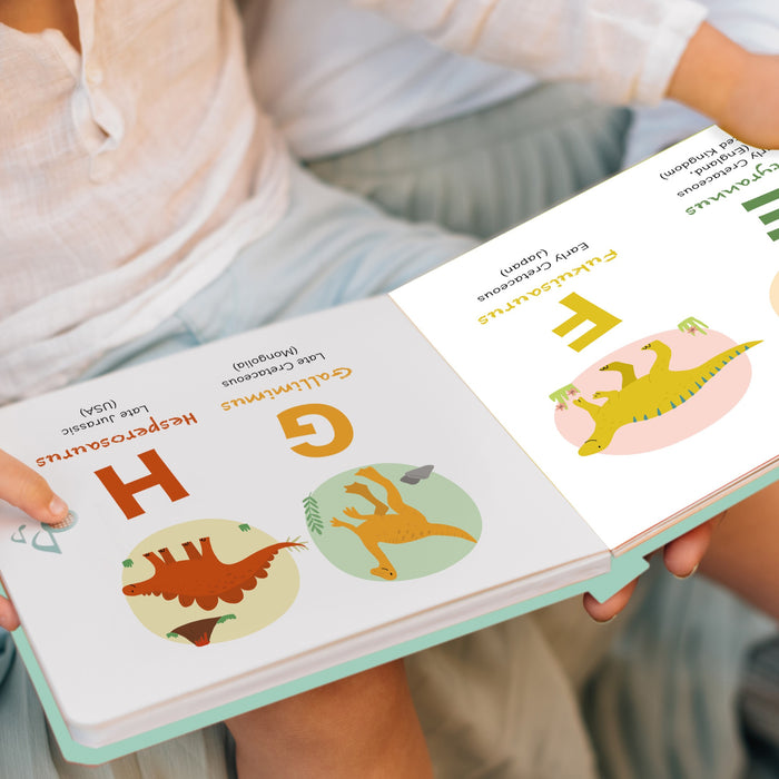 Close up of a child's hand holding an open dinosaur book. Dinosaurs, fun activities, education, children books.