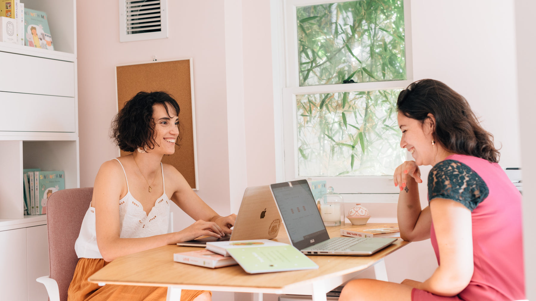 Two women are working on their laptops at a desk. Publishing house, small business, work from home.