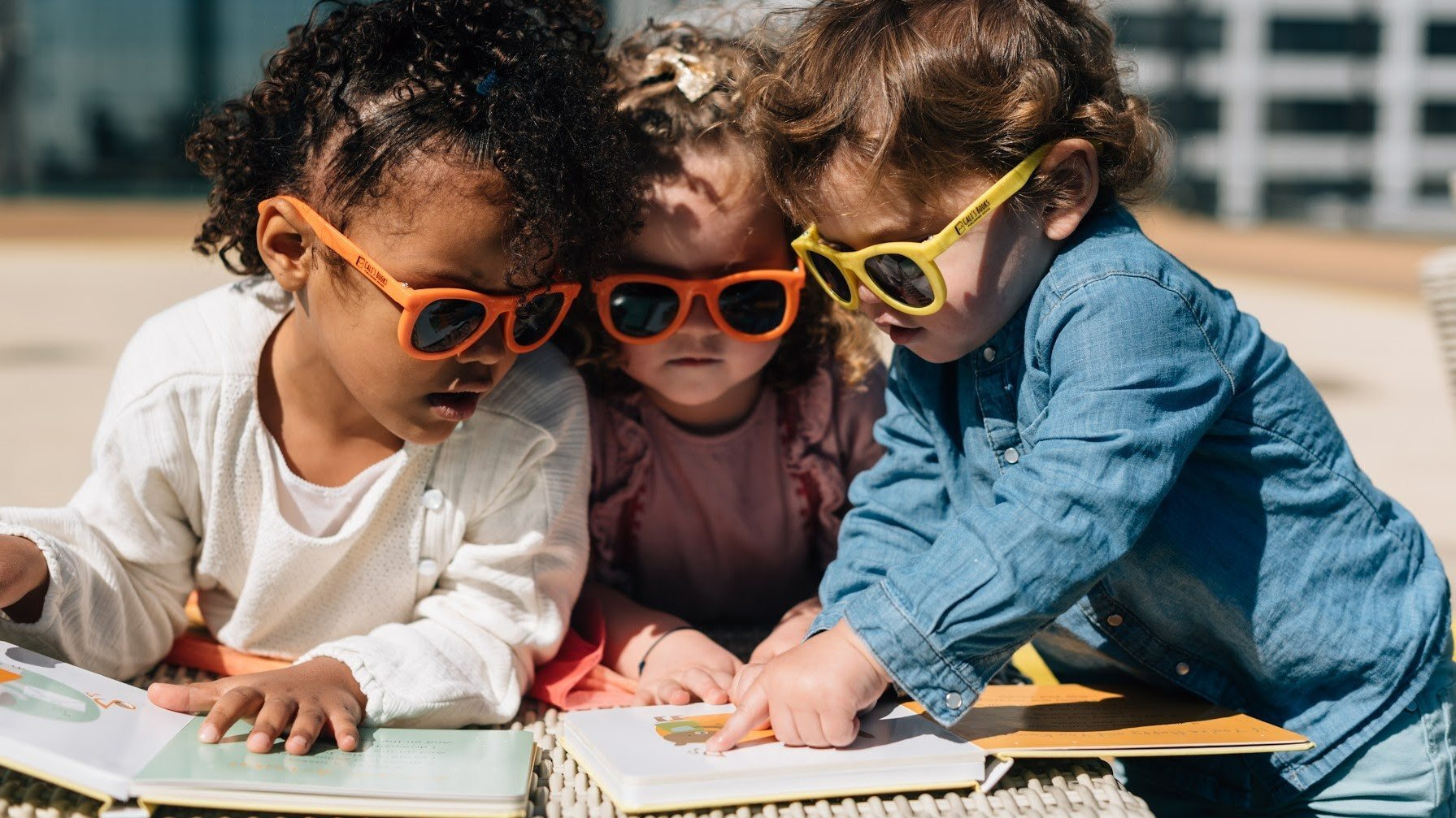 Three kids are reading on the beach. toddler books, fun educational activities