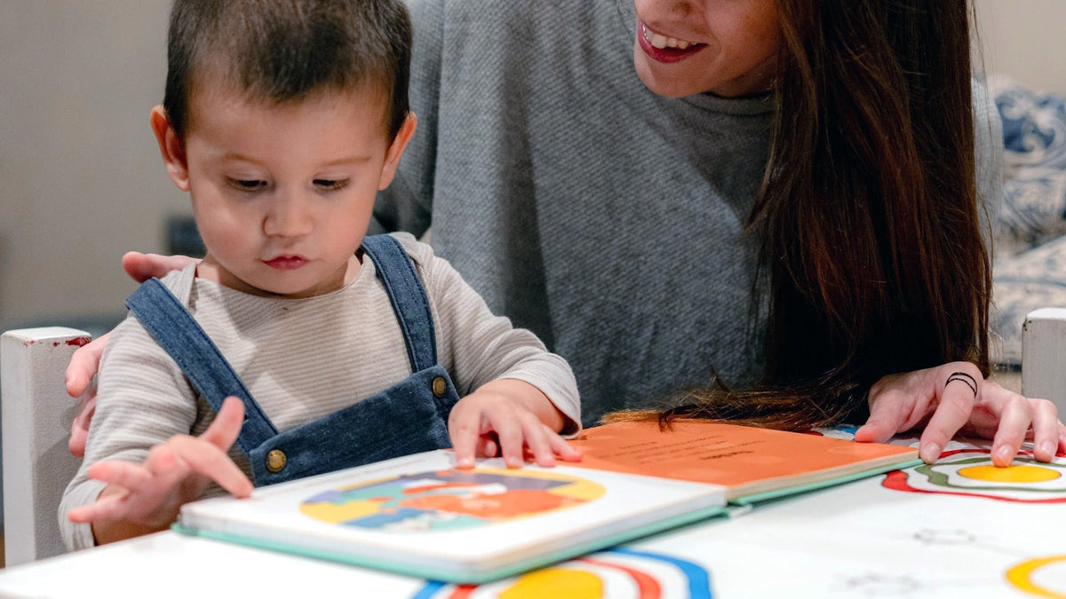 Mom and toddler are listenign to a sound book
