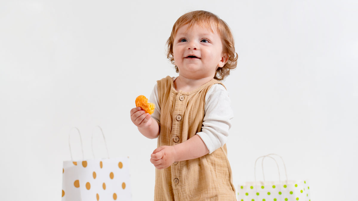 A toddler girl is posing next to gift bags. First birthday book, books for toddlers, books for babies, gifts for babies, gifts for toddlers.