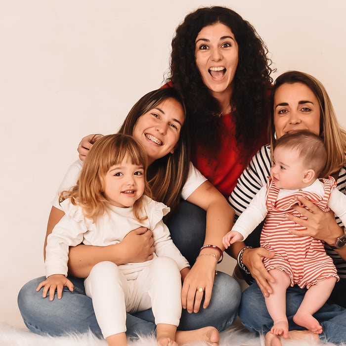 Three women are posing and laughing with two toddlers. Parenting hacks, kids activities, educational fun.