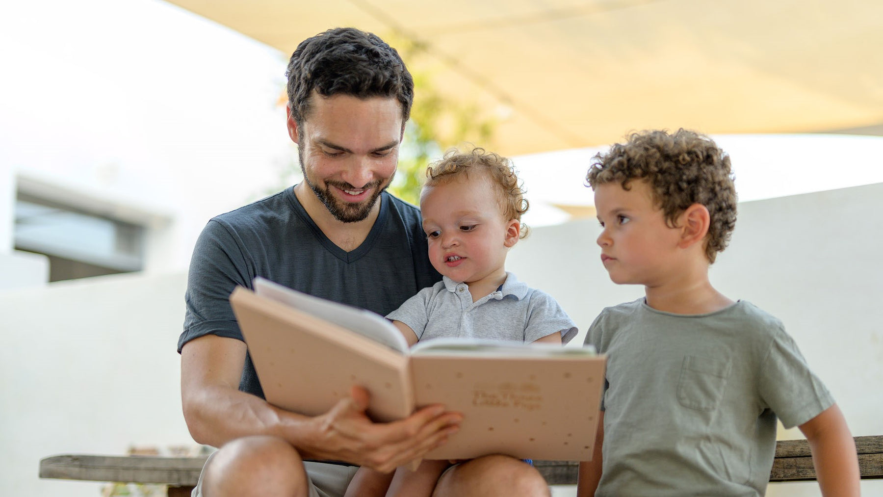 A Dad is reading a book to his two children. Fun, educational, activities for kids.