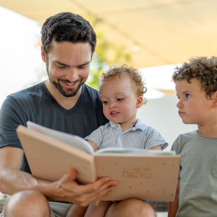 A Dad is reading a book to his two children. Fun, educational, activities for kids.