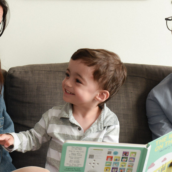 A Mom and a Dad are reading a book to their toddler. Best parenting books, toddler, kids activities, education.
