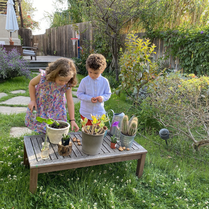 2 children planting flowers in honor of earth day.  Earth month, kids activities, outdoor kids activities 