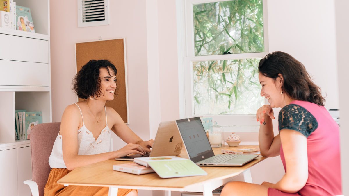 Two women are working on their laptops at a desk. Publishing house, small business, work from home.