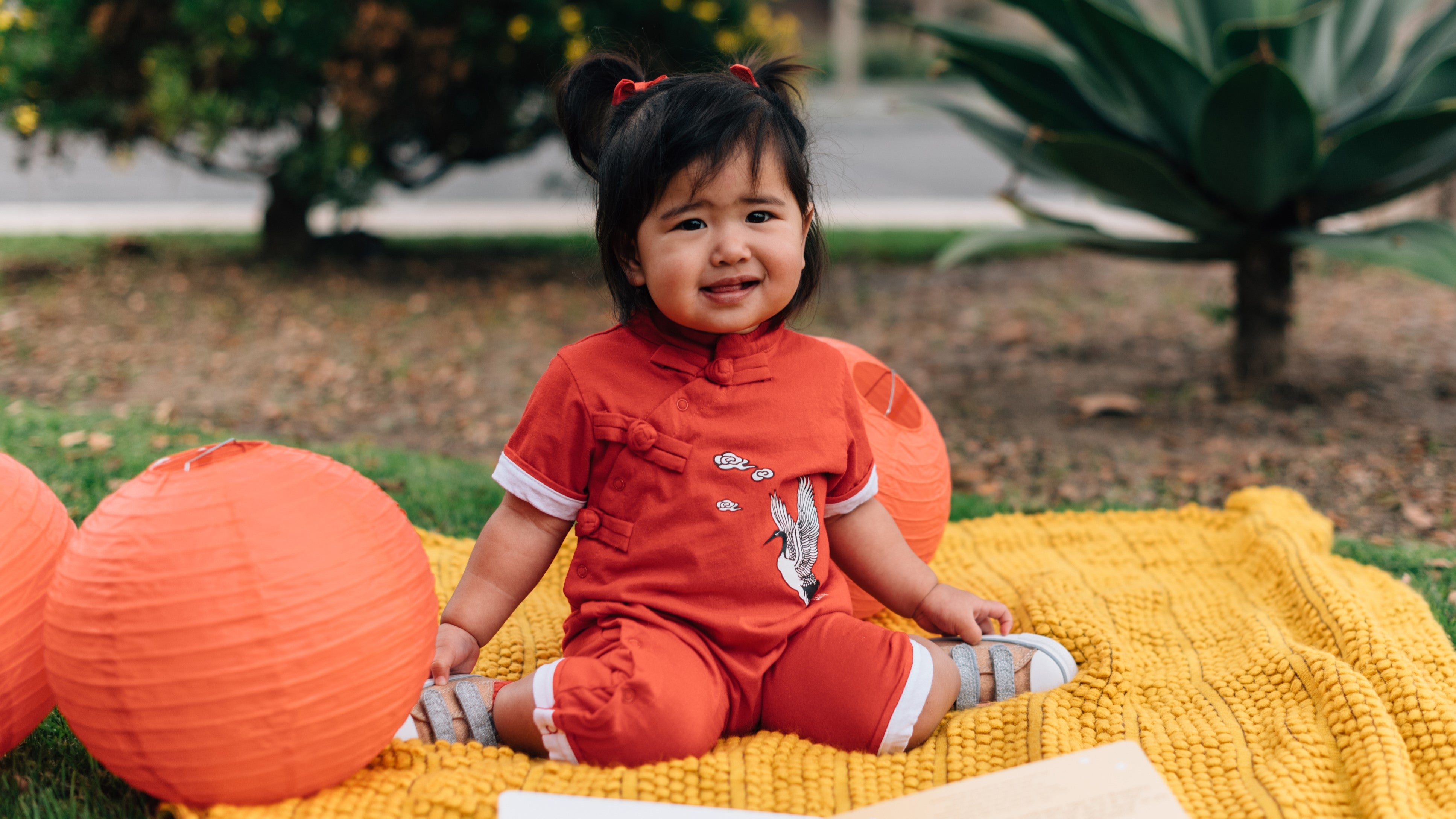 A young girl is sitting outside with red lanterns. Chinese new year, lunar new year, family celebration, gifts ideas