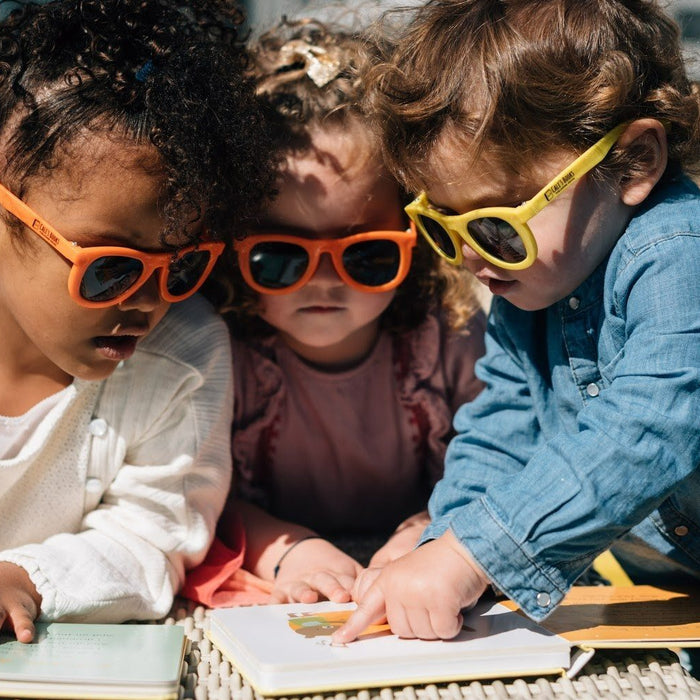 Three kids are reading on the beach. toddler books, fun educational activities