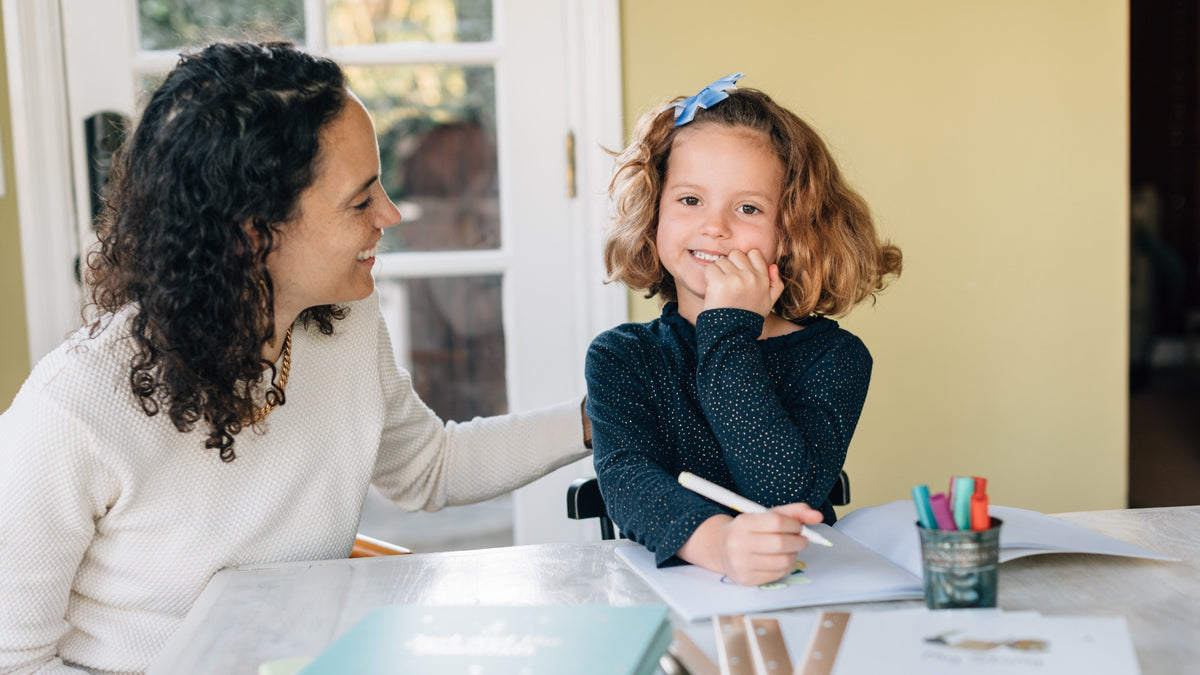 A Mom is looking at her daughter who's drawing. Mother's Day, gifts ideas, kids activities. 