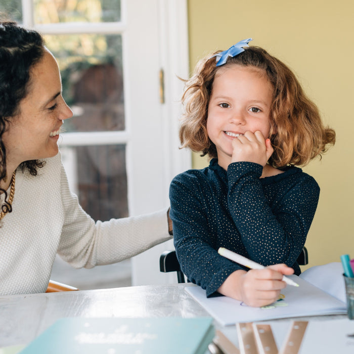 A Mom is looking at her daughter who's drawing. Mother's Day, gifts ideas, kids activities. 