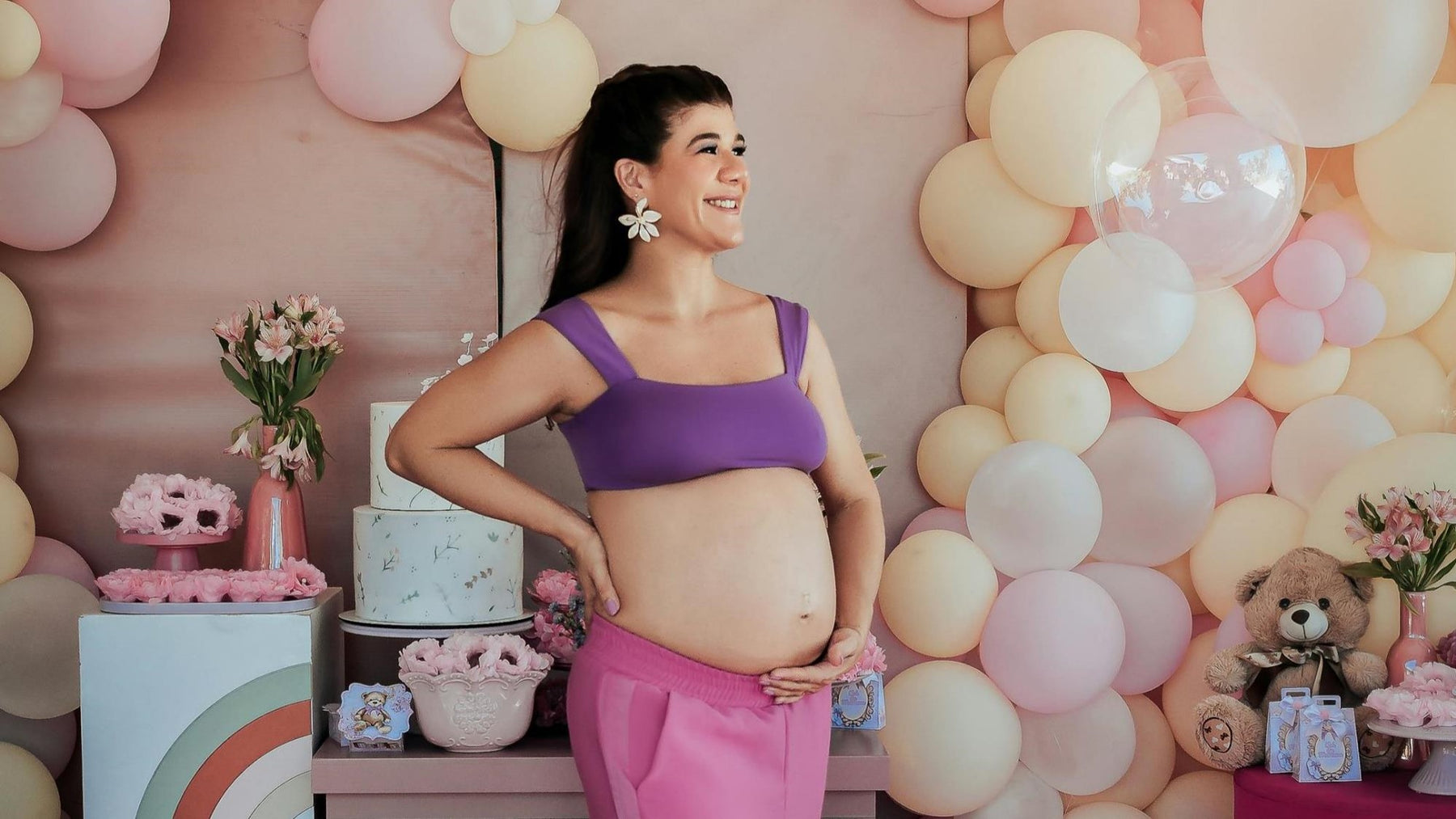 A pregnant mom is posing at her baby shower with balloons and cakes. Baby shower, ideas, activities, themes, games.