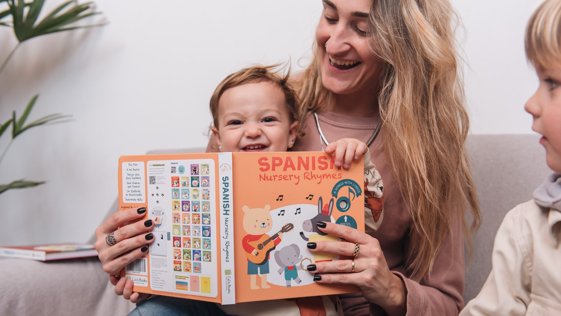 A Mom is reading a book with her two kids. Fun children activity, bilingual books. 