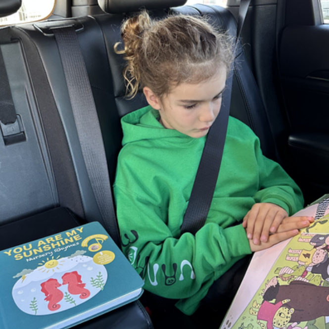 A girl is reading picture books in the car. Kids, fun activities, educational books.