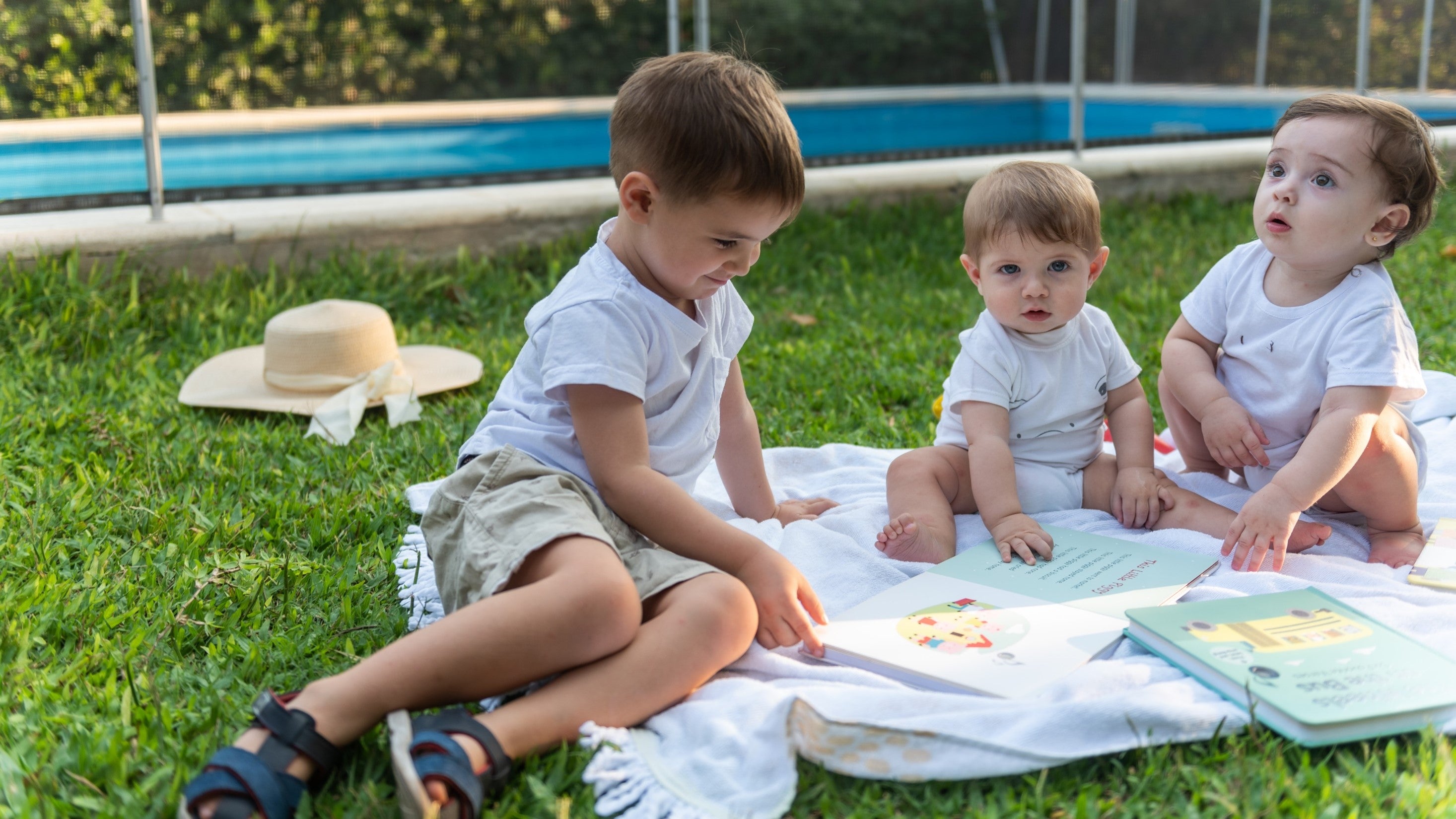 Three children of various ages are reading books in the garden. Reading, kids, infant, toddler, activities, fun, educational.