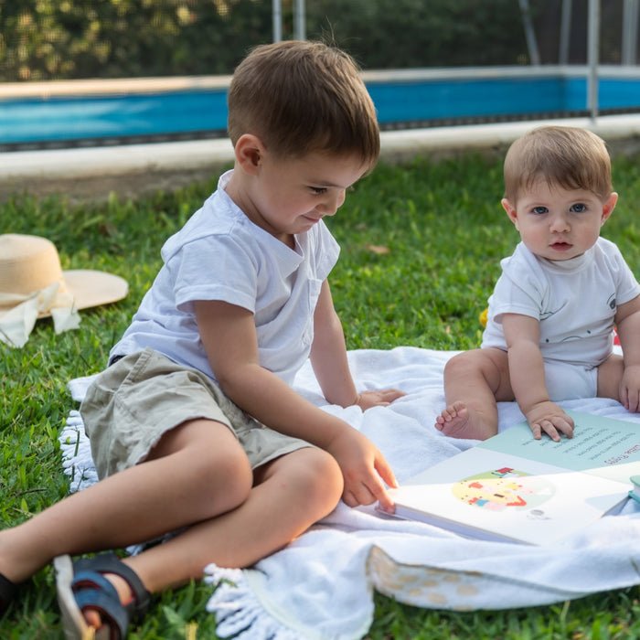 Three children of various ages are reading books in the garden. Reading, kids, infant, toddler, activities, fun, educational.