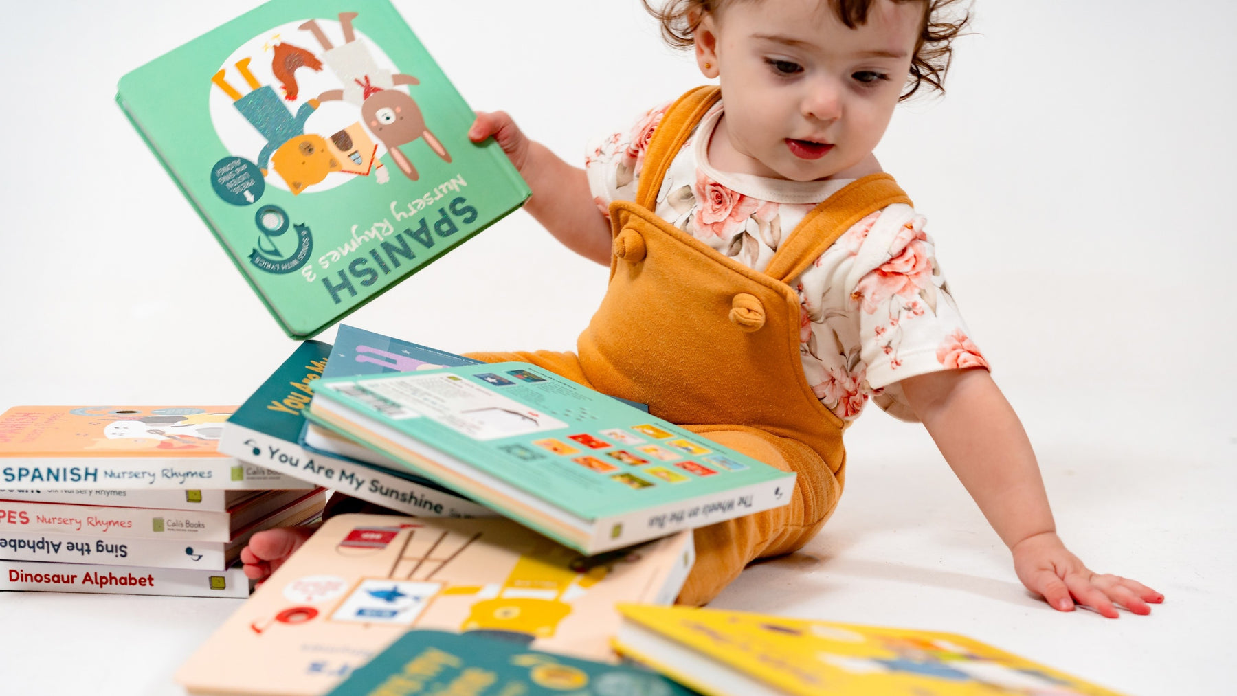 A toddler is picking a book from a pile of book. Nursery rhymes, children's books, fun activities, educational.