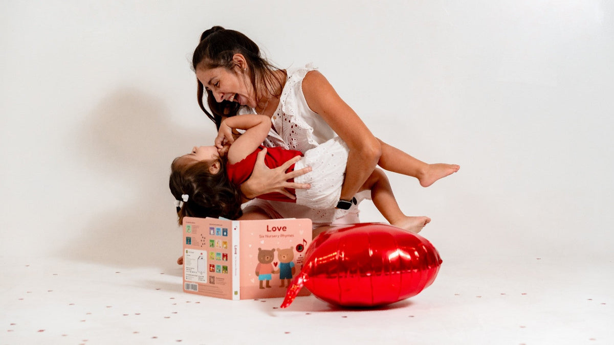 A mom is laughing while holding her little girl in her arms. Musical activities, kids songs, mothers day, mothers day gifts.